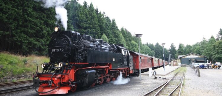 Dampflokomitive der Brockenbahn der Harzer Schmalspurbahn am Bahnhof Schierke mit Dampf und Personenwaggons